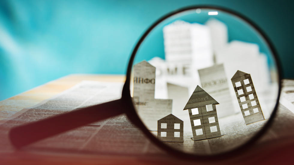 Photo illustration of magnifying glass examining housing listings.
